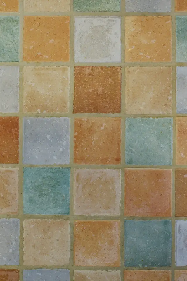 Carreaux carrés aux tons ocre, sable, vert d'eau et bleu gris, posés en damier irrégulier