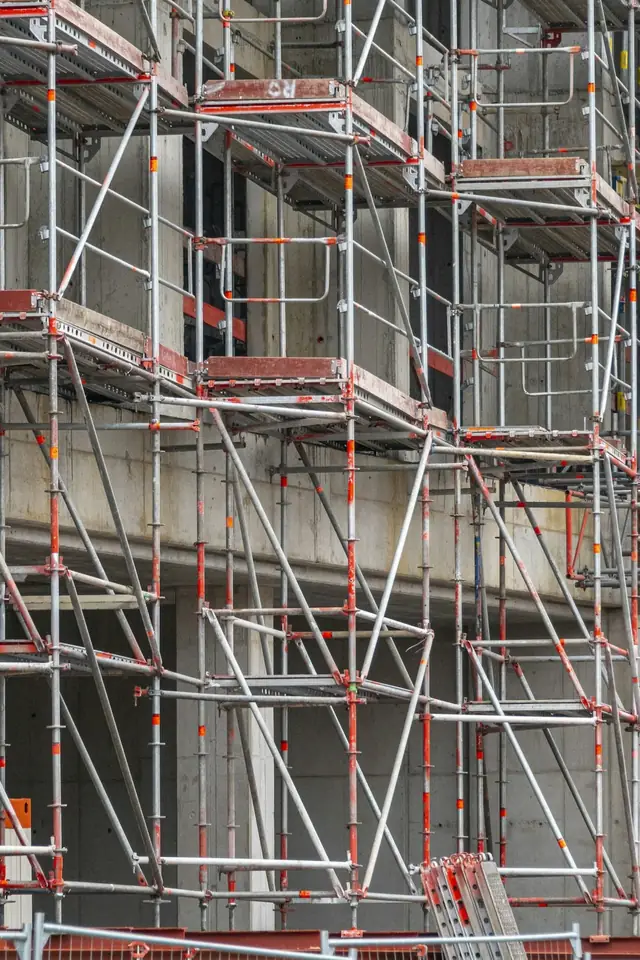 Ouvrier debout sur un échafaudage dressé contre la façade d'un immeuble
