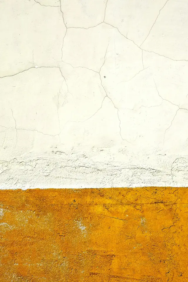 Enduit blanc craquelé au-dessus d'un soubassement ocre orangé