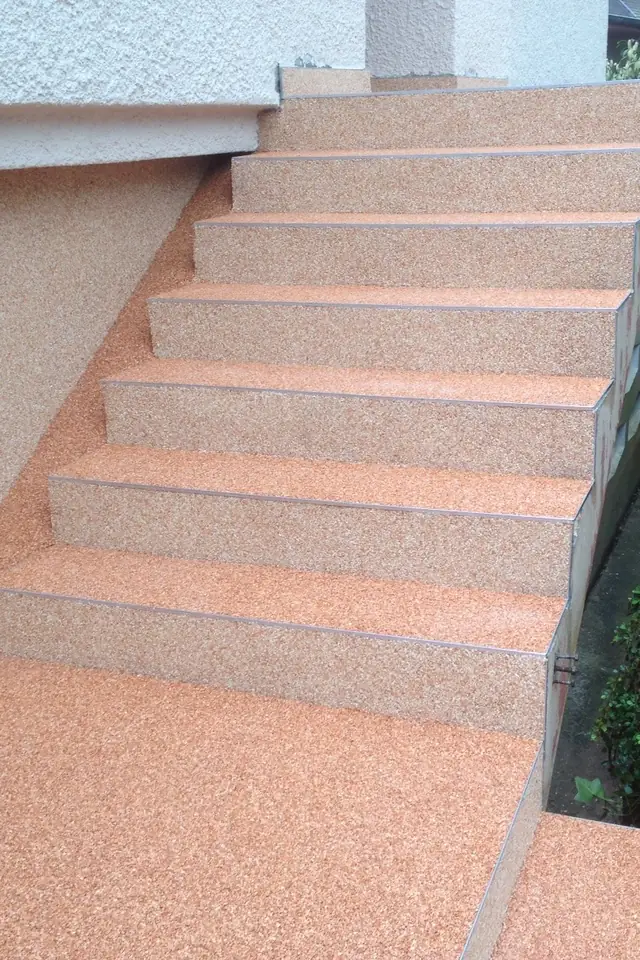 Marches d'escalier extérieur habillées de moquette de pierre rosée, haie sur le côté