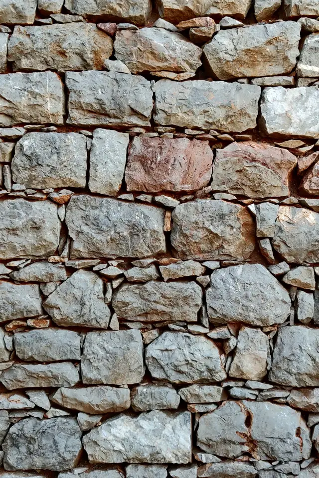 Mur ancien en moellons de pierre grise et ocre, hourdés au mortier clair