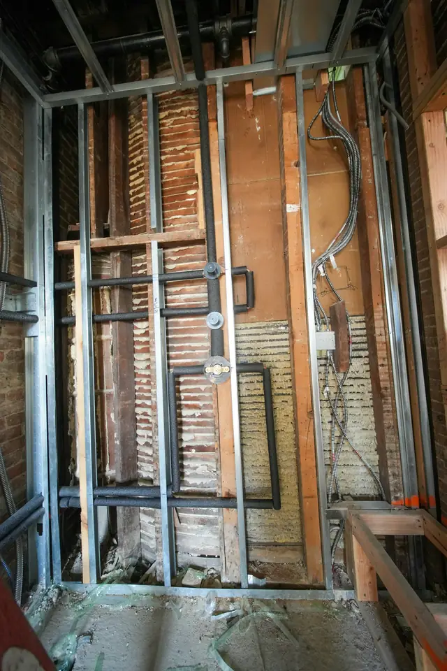 Ossature métallique d'une cloison en cours de montage, gaines électriques et rails au sol