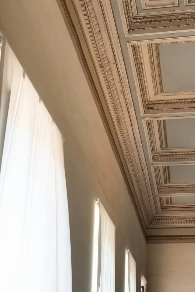 Pièce très haute sous plafond : plafond à caissons, voilages blancs devant de grandes fenêtres