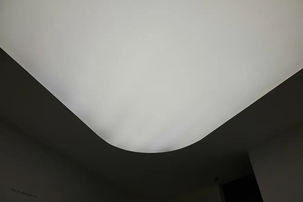 Plafond blanc parfaitement lisse aux bords arrondis, au-dessus d'un mur sombre