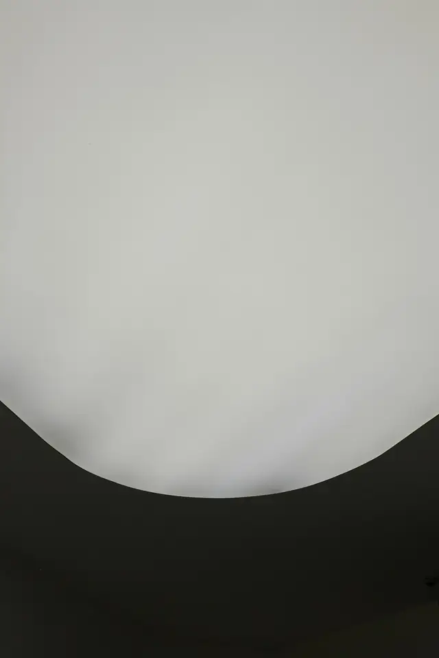Plafond blanc parfaitement lisse aux bords arrondis, au-dessus d'un mur sombre