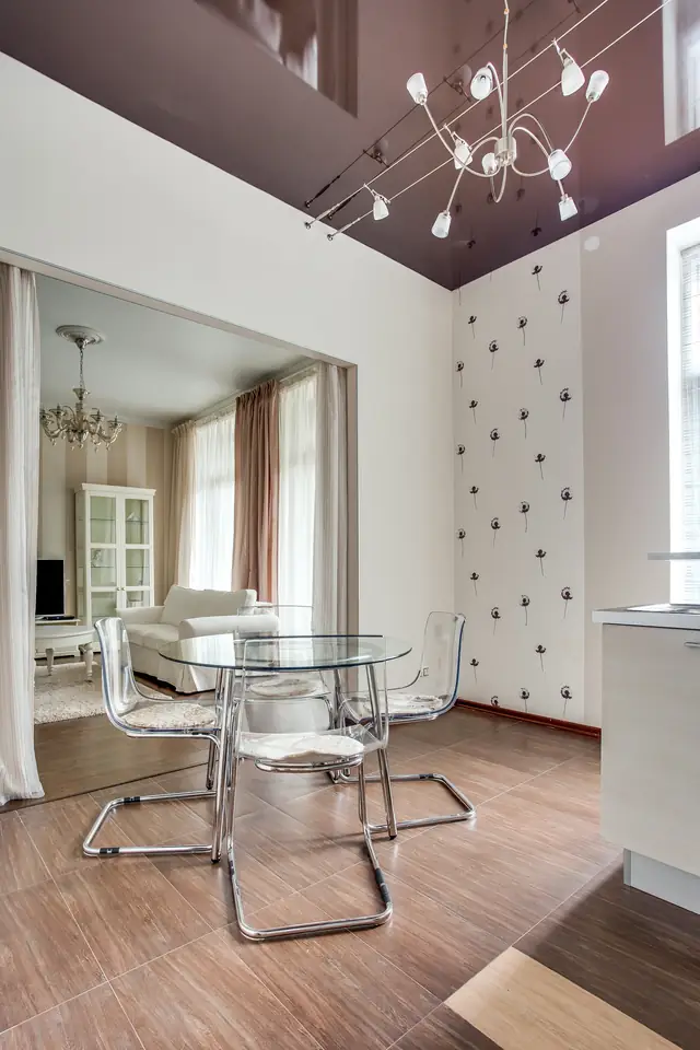 Salle à manger sous un plafond tendu laqué qui reflète la pièce, suspension à branches