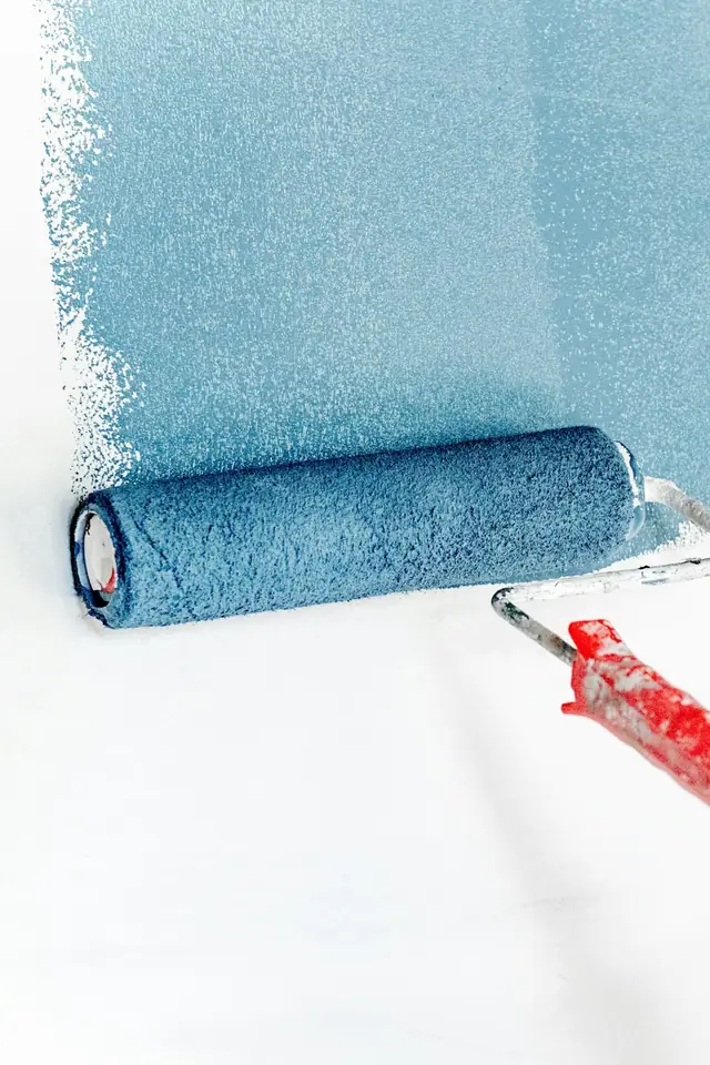 Rouleau chargé de peinture bleue passé sur un mur blanc