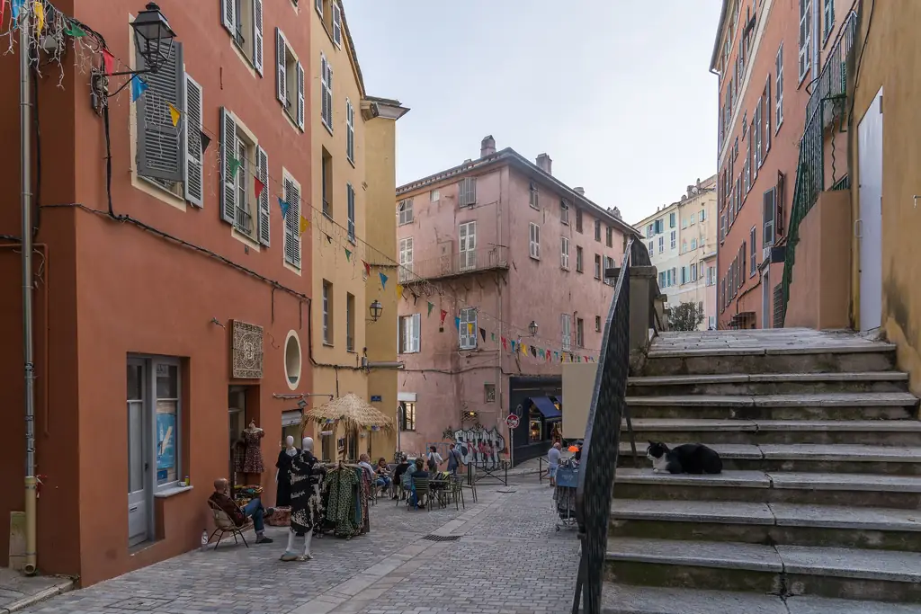 Rue des Terrasses à Bastia : façades rouge brique et rose pâle, volets, escalier de pierre