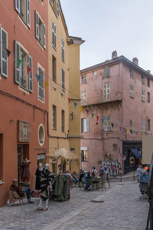Rue des Terrasses à Bastia : façades rouge brique et rose pâle, volets, escalier de pierre