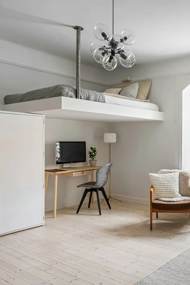 Salon clair à grande hauteur sous plafond, fenêtre cintrée, lit en mezzanine au-dessus d'un bureau