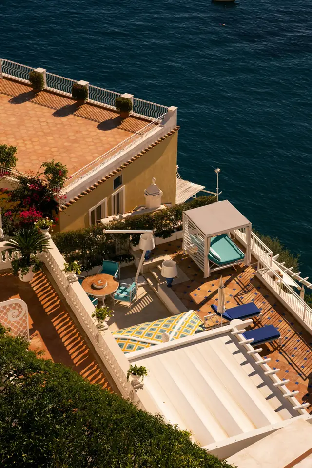 Terrasse carrelée de terre cuite au-dessus de la mer, transats et escalier blanc, vue d'en haut